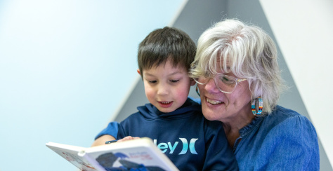 An older adult is reading a book to a young child.